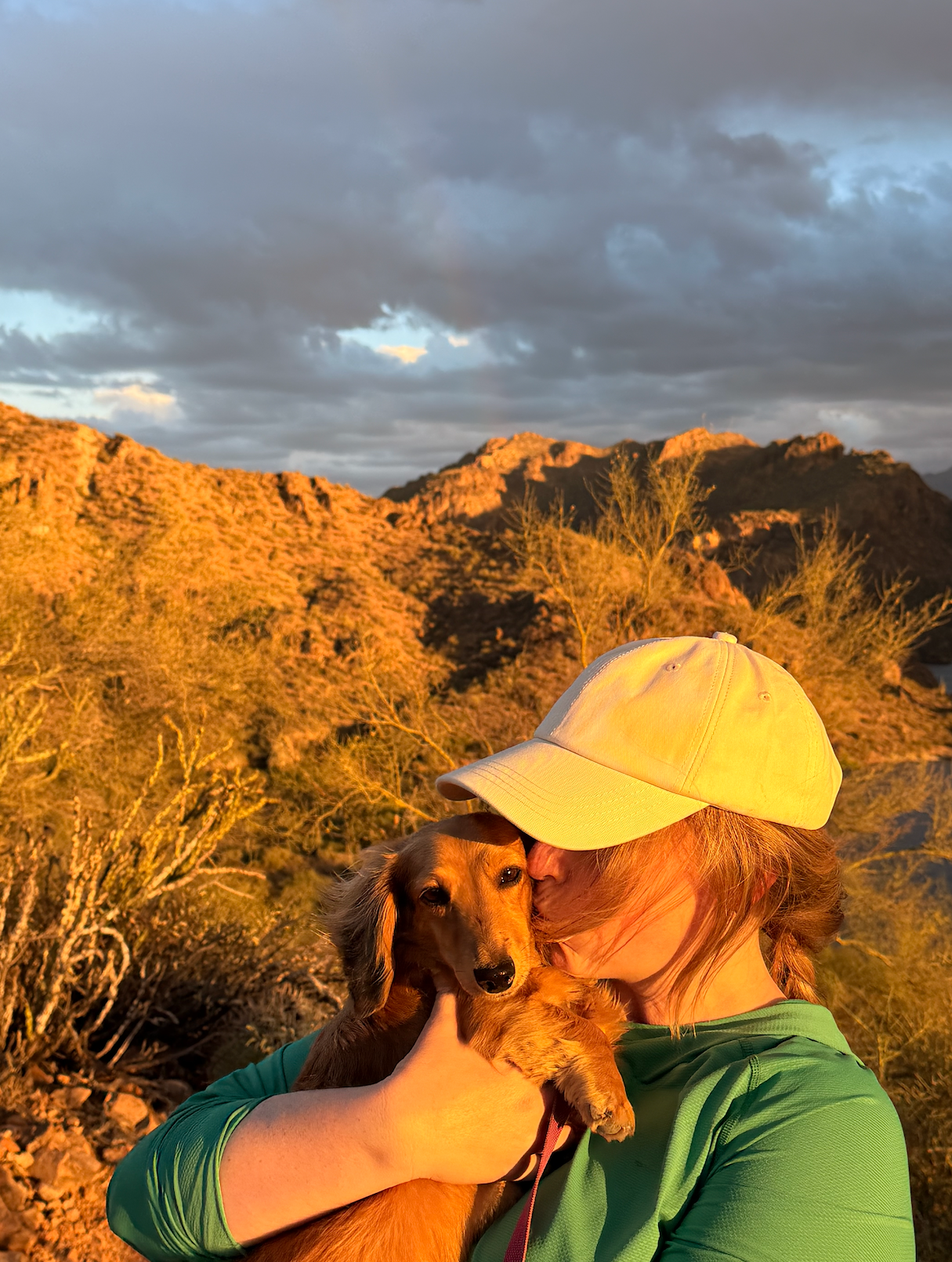 girl kissing a dachshund while hiking