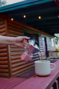 girl holding a moka pot pouring into a coffee cup