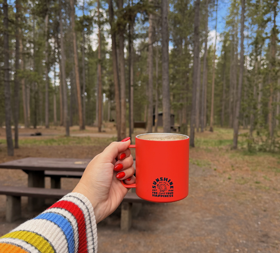 girl holding up a red rei camp cup