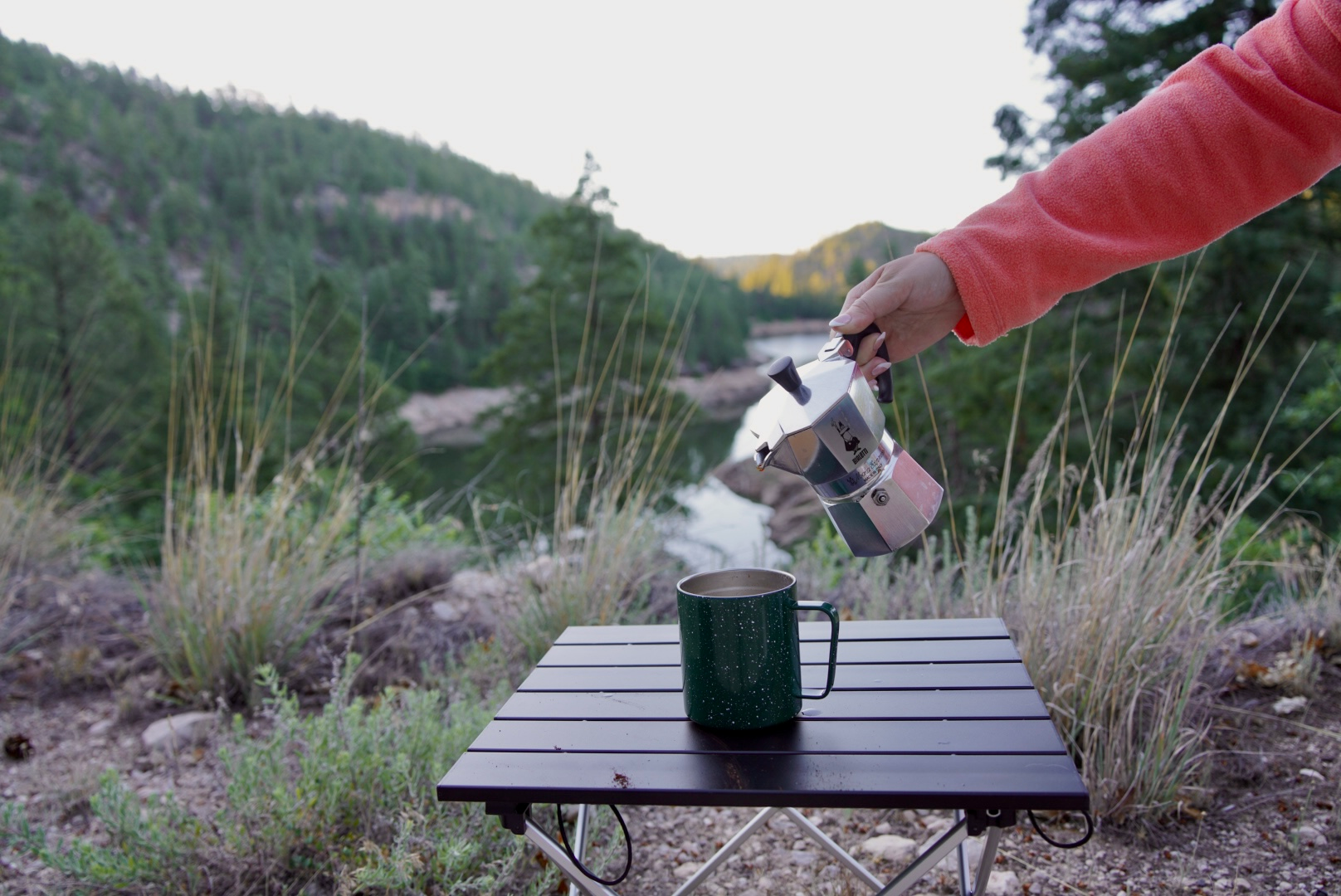 girl in pink sweater pouring coffee out of a moka pot in blue ridge reservoir in arizona