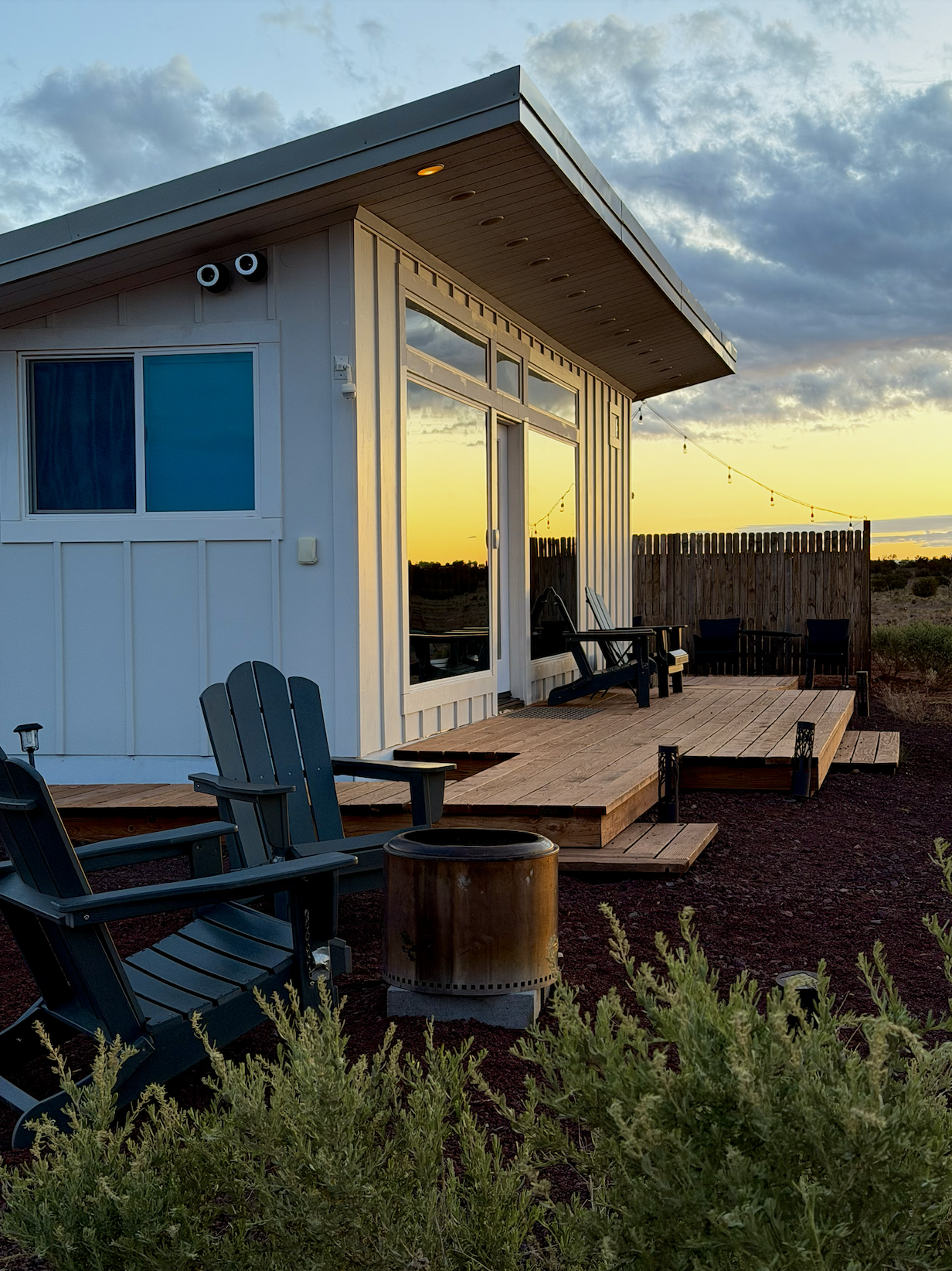 modern white bungalow with wood deck and Adirondack chairs at sunset near the Grand Canyon