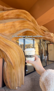 Exterior of Haute Coffee in Tucson, Arizona, featuring the café's curved architectural entrance with a takeaway coffee in the foreground.
