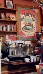 Espresso bar inside Macy's European Coffee House in Flagstaff, Arizona, featuring vintage décor, an espresso machine, and a colorful coffeehouse poster.