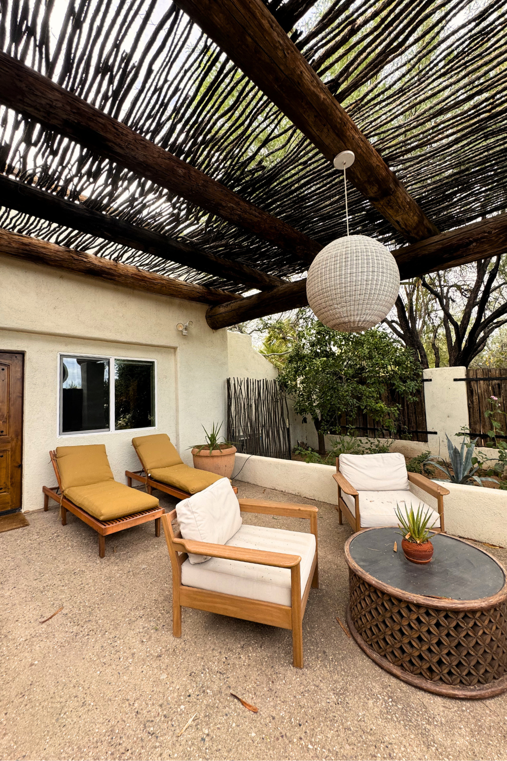 Outdoor patio with lounge chairs, wooden pergola, and desert-inspired seating area at a boutique hotel in Tucson, Arizona.