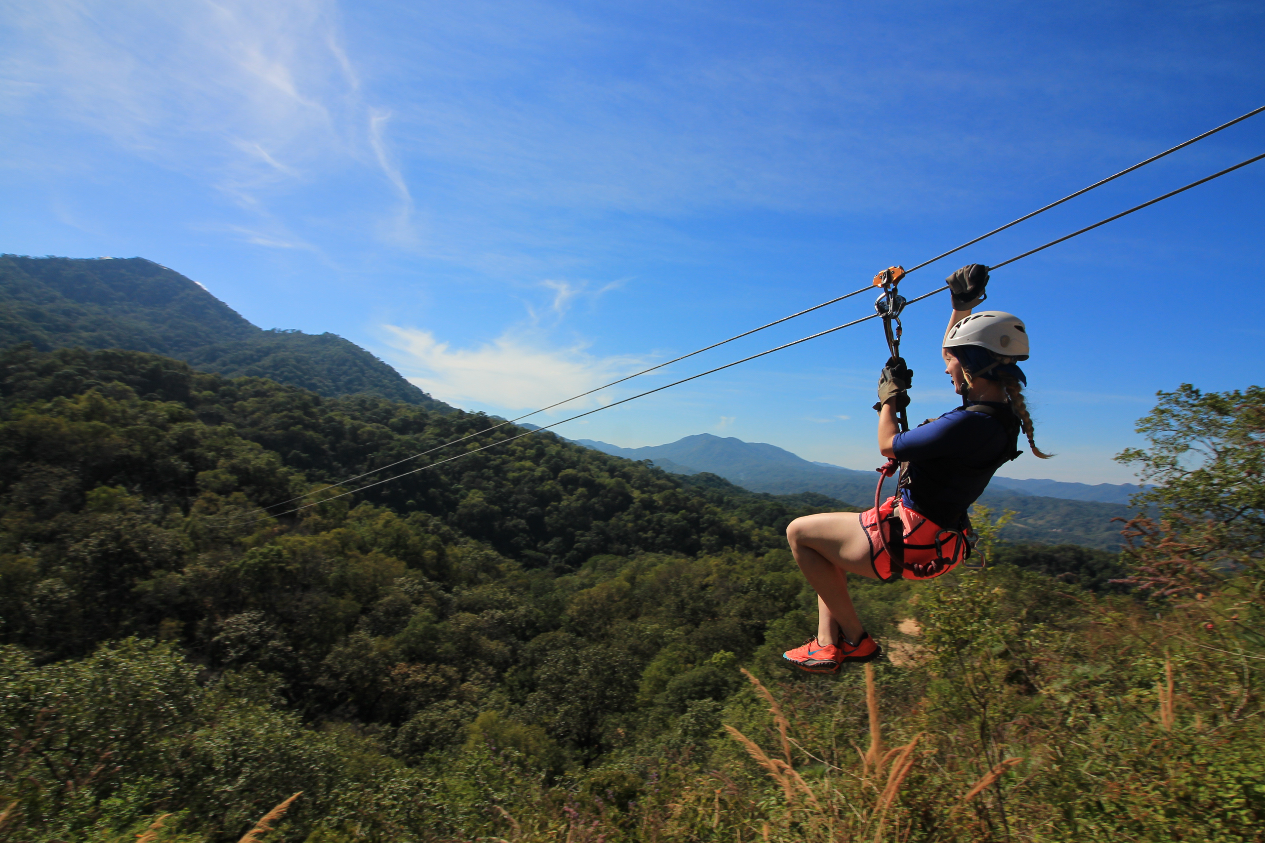 girl ziplining through the forest