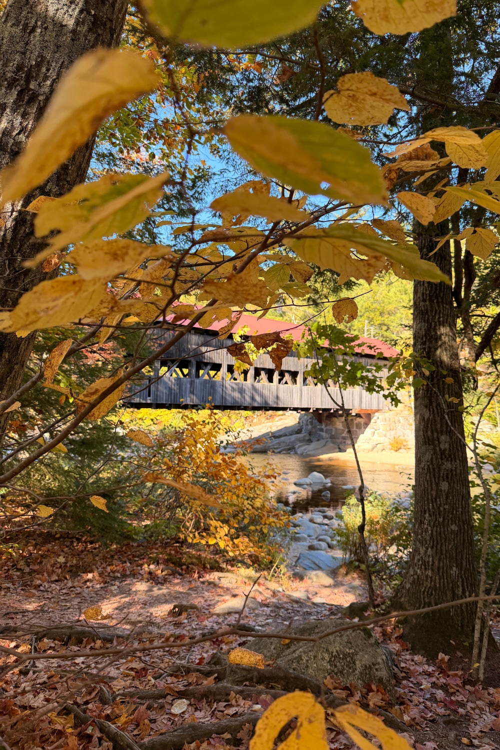 Covered bridge surrounded by colorful fall foliage along the Kancamagus Highway in New Hampshire.
