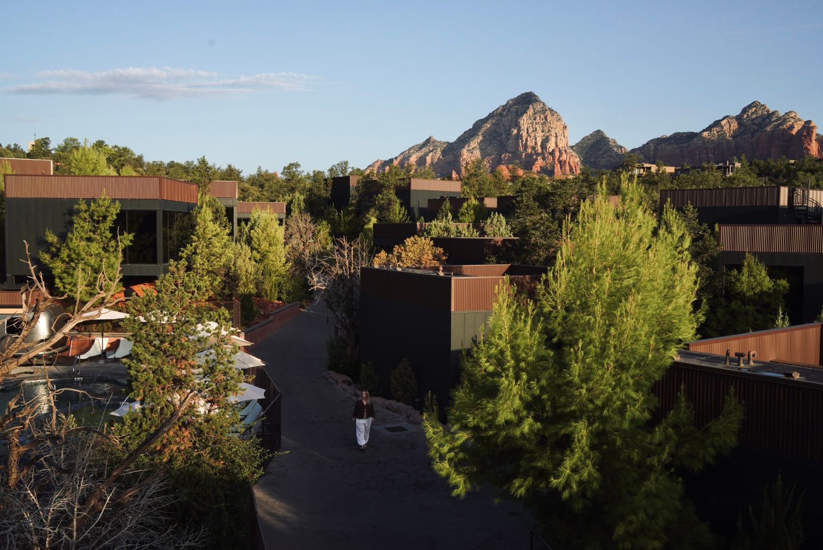 Modern villas at Ambiente Sedona surrounded by desert greenery, with red rock formations rising in the background.